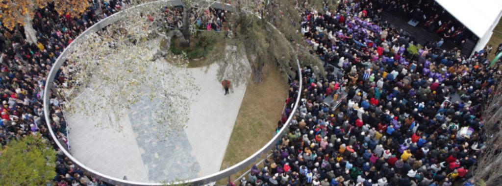 Fotografía aérea del memorial de ex presas políticas y un gran público mirando un escenario.